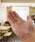 Dead Simple 3.5 Inch Clear Valance Clips For Window Shades 5 Pack Universal mount bracket held in a hand in a kitchen setting.