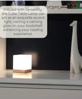 Square Glass Desk Lamp Cube LED Light With Warm 2700K Lit Glow on shelf with giraffe ornament and book