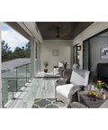 Modern patio with wicker chairs, glass railing and ceiling fan. Endicott Collection 1-Light Outdoor Wall Lantern seen by sliding door.