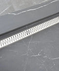 Twenty Three Half Inch Linear Shower Drain With Heavy Gauge Stainless Steel Frame And Ocean Wave Pattern in modern bathroom setting.