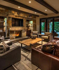Cozy living room with stone fireplace, leather and striped sofas, showcasing Top Shelf Water Based Reactive Wood Stain Delivers A Real Deal Aged Barrel Finish.