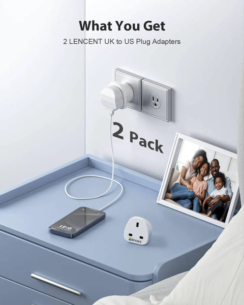 UK To US Plug Adapter 2 Pack Go-To Grounded Travel Converter for Travelers on a blue shelf with devices and a photo frame.