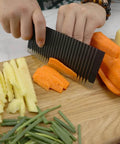 Ciieeo stainless steel crinkle potato cutter, side view slicing orange carrot on cutting board with potatoes nearby