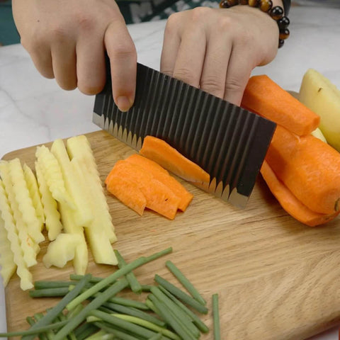 Ciieeo stainless steel crinkle potato cutter, side view slicing orange carrot on cutting board with potatoes nearby