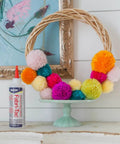 Fast Drying Fabric Glue For Fabrics Canvas Lace Wood And More That Dries Crystal Clear In Minutes And Forms A Permanent Bond Fully Cures In 24 Hours Ideal For Repairs Crafts Hems And Transformations It Works Like A Charm 8 Ounce Bottle Two Pack with colorful pom-poms on a wreath