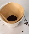 Porcelain Coffee Dripper Size Four, White Ceramic, Manual Pour Over Filter Holder with coffee and filter setup.