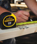 A person marking wood with FatMax 25 Foot Tape Measure 2 Pack Built Tough For Job Sites with 11 Foot Standout.
