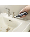 Person using Ultra Compact Four Volt Cordless Rotary Tool featuring variable speed to clean sink area with tarnished faucet.