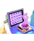Heavy Duty UV Curing Lamp With 365Nm 395Nm And 405Nm Bands illuminating pink resin figure with various small sculptures.