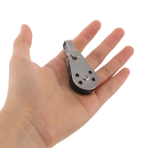 Person holding a stainless steel cable pulley block, part of a set of 4 with bearings, designed for kayak and marine gear use.
