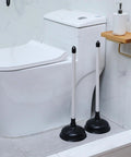 Top Shelf Heavy Duty 12 Pack Toilet Plungers Total Game Changer For Any Household With Rock Solid Extra Long Grip Handle And Insane Suction Power To Straight Up Crush Stubborn Bathroom Clogs Fast In Black, two plungers beside a toilet.