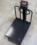 Built Different 24X32 Digital Platform Scale Crushing 1000 Lbs Load Limit With Snappy 0.2 Lbs Readability on a diamond plate surface.