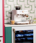 Next Level Semi Automatic Espresso Machine With Badass Built In Grinder And Silky Milk Frother Featuring WiFi App Control Custom Drinks 15 Bar Pump 95 Oz Water Tank Matte White Copper Accents on kitchen counter.