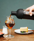 650ml Cold Brew Coffee Bottle With Removable Filter Heatproof Glass pouring coffee into a glass, cake on table