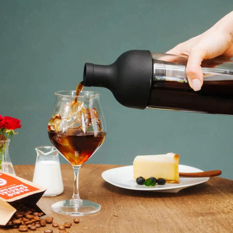 650ml Cold Brew Coffee Bottle With Removable Filter Heatproof Glass pouring coffee into a glass, cake on table