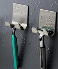 Rainy wall with two mounted silver razor holders, holding black and green razors, featuring No-Drill Stainless Steel Razor Holder With Adhesive, Wall Mounted Shaving Organizer, Plug Hook And Storage Rack For Bathroom And Kitchen, Silver, 2 Pack, Easy Setup. Rust-resistant.