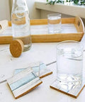 Glass of water on wood table with coasters and tray in background
