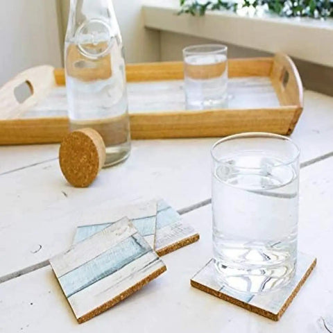 Glass of water on wood table with coasters and tray in background