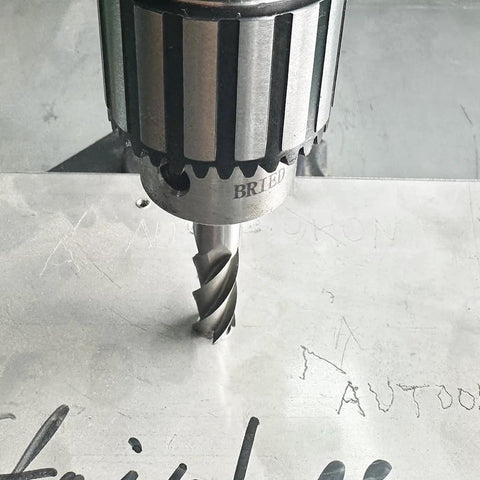 HSS 4-flute straight end mill cutter in a drill chuck cutting into a metal plate.