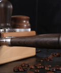 Close-up of the smooth wood ergonomic handle of a 58mm Bottomless Portafilter Featuring Smooth Wood Ergonomic Handle And Double Shot Filter Basket For Breville Oracle Espresso Machines Real Deal Barista Rig.