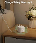 Ultra Compact Six Outlet Surge Protector With Three AC Outlets And Three USB Ports on a nightstand, charging devices.