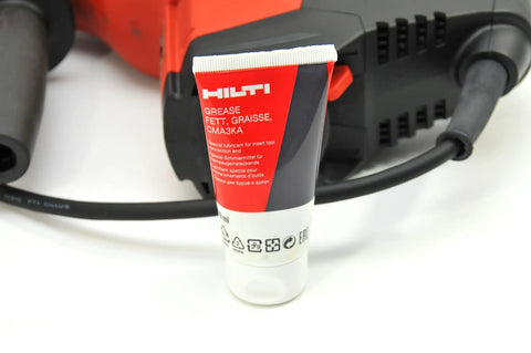 Tube of grease next to Beast 120V Rotary Hammer Drill Kit TE 7-C With D-Grip, emphasizing maintenance for heavy-duty use.