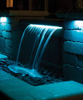 Outdoor waterfall illuminated by LED Color Changing Hardscape Light 6-Inch Multicolored With Oil Rubbed Bronze Finish.