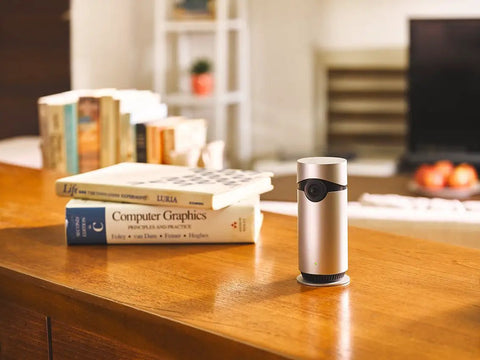 Indoor Home Security Cam With 180 Degree View Full HD 1080p Night Vision Two Way Audio MicroSD Recording Works With Apple HomeKit Easy Voice Control For Scene Creation on wooden table in living room.