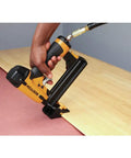 Hand using a yellow pneumatic flooring nailer on wooden floor, not the Ascend Desktop Stapler With Antimicrobial Staples Built In Remover StapleStore