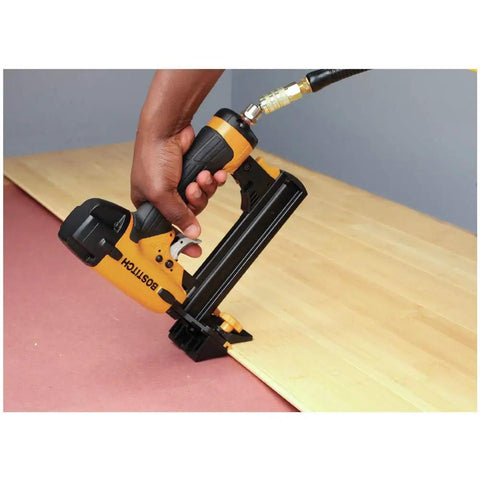 Hand using a yellow pneumatic flooring nailer on wooden floor, not the Ascend Desktop Stapler With Antimicrobial Staples Built In Remover StapleStore
