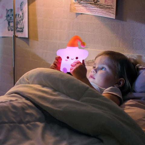 Cute Stars Night Light For Baby Nursery, Color Changing Silicone Star Lamp held by child in bed, soft glow atmosphere