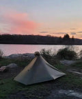 Gatewood Cape Ultralight 11 Oz Backpacking Tarp Shelter And Poncho Canopy, pitched by a lakeside at sunset, green.