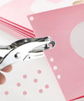 Two Piece Metal Hole Punch Set With One Quarter Inch And One Eighth Inch Single Hole Punches used on pink paper for crafting.