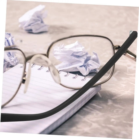 Metal eyeglasses with black temple arms resting on notepad next to crumpled paper. Two Pairs Metal Eyeglass Temple Replacement Arms Kit For Fast Easy Repairs Ergonomic Durable Design For All Day Comfort Sturdy Construction Fits Standard Frames Quick Fix For Glasses visible.