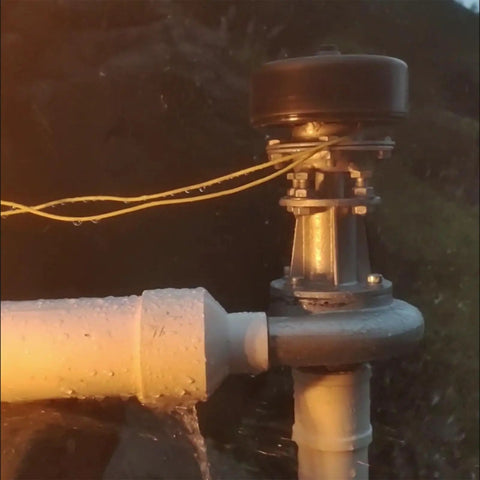 Close-up of Impact Type Portable Hydropower Turbine Generator 1000W 220V for home use, showing pipes and water flow mechanism at dusk.