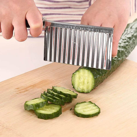 Stainless steel crinkle cutter with wavy blade slicing cucumber on cutting board