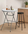 32 Inch Plastic Folding Round Bar Height Table With Gray Metal Finish For Outdoor Parties Cafes Restaurants Backyard Weddings Durable HDPE Construction 350 Lb Capacity Easy Setup White beside a black stool in a modern kitchen setting
