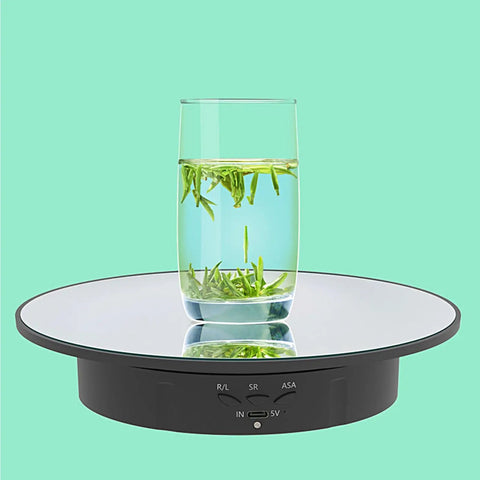 Electric Motorized Rotating Display Stand With 360 Degree Turntable For Product Photography Jewelry Cake And 3D Models That Spins Smoothly shows a glass of water and green tea leaves.