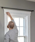 Person installing Indoor Window Shrink Film Insulation Kit For Five Windows 62 Inch By 210 Inch Crystal Clear Film With Eighty Four Foot Double Sided Tape on window.