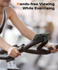 Woman using MagSafe Gym Phone Mount With 17 N54 Strong Magnets Adjustable Strap 3 In 1 Phone Holder on exercise bike handlebars.
