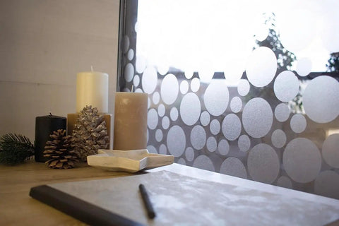 Milky Privacy Window Film With Reusable Static Cling No Fuss Removable And Repositionable For Glass Surfaces 26 By 59 Inch Roll Ideal For Windows Doors Showers Cabinets And More Easy Cut Peels Off Cleanly installed on window with circular patterns next to candles and pine cones.