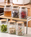Assorted vintage glass jars with lids on a shelf, showcasing airtight food storage for coffee, tea, sugar, and snacks.