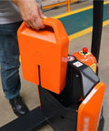 Close-up of Kick Ass 3300 lb Capacity Electric Pallet Jack For Tight Spaces with operator holding battery pack.