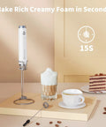 Rechargeable Milk Frother With 3 Heads, USB C Handheld Foam Maker, Waterproof Detachable Stainless Steel Whisk, Stand Included, Electric Drink Mixer For Lattes And Cappuccinos, Rich Foam Anytime shown with a cappuccino and slice of cake.