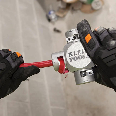 Hands using Large Cable Stripper For 2/0 To 250 MCM Cables With Clover Design for precise insulation removal on red cable.