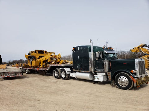 Truck with trailer transporting equipment, secured by Ratcheting Chain Binder Three Eighths To One Half Inch Four Pack Load Binders.