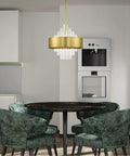 Absolute Flex Eight Light Natural Brass Pendant Chandelier With Sculpted Drum Shade And Dazzling Clear Crystal Rods For Upscale Living Areas That Turn Heads On A Dime above a round black dining table with green velvet chairs.