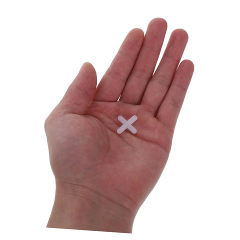 Hand holding a small white cross-shaped tile spacer for 500Pcs Tile Leveling Spacers Set Reusable Cross Shape Tile Alignment Tools For Quick Wall And Floor Tiling Durable 4mm Leveler Spacers For Easy No Fuss User Friendly Tiling Projects
