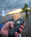 Angler holding Extra Bluetooth I Pilot System Remote For Trolling Motors with large LCD and ergonomic buttons on a boat.