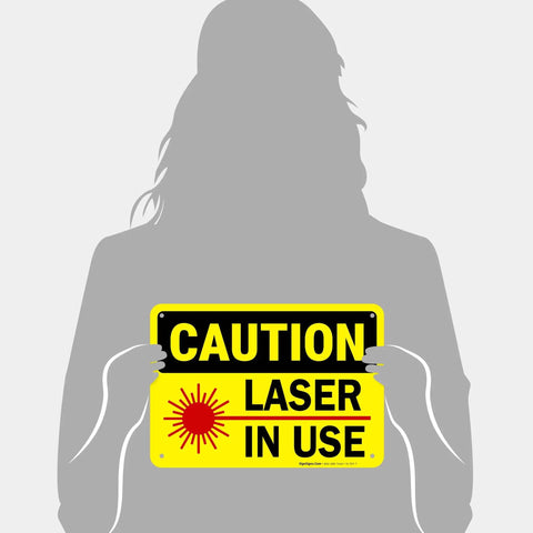 Laser In Use Sign Caution Sign 10x7 Inches Rust Free Aluminum Fade Resistant Indoor Outdoor Safety Sign For Shops And Factories And Industrial Spaces Made In USA displayed by person